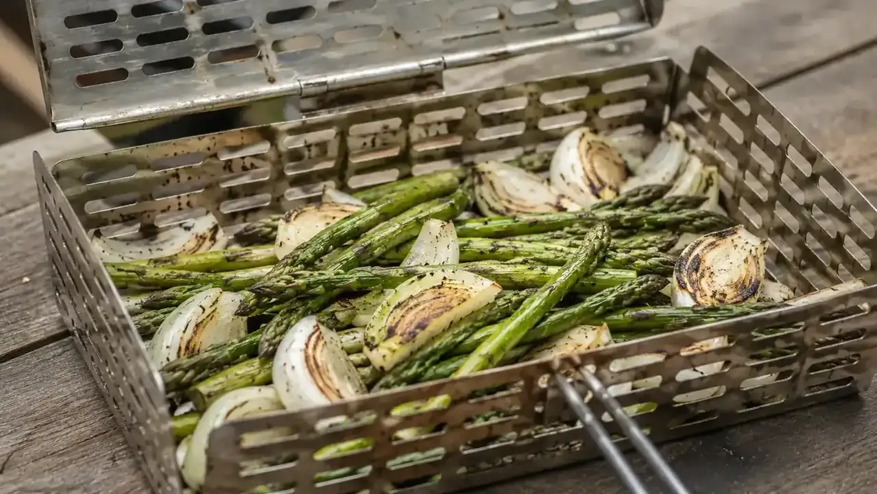 Grill basket with asparagus spears showing char marks after grilling