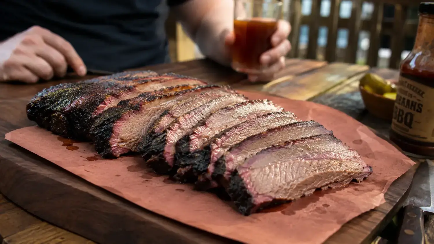 Sliced brisket showing moist interior, smoke ring visible, on a butcher paper lined cutting board